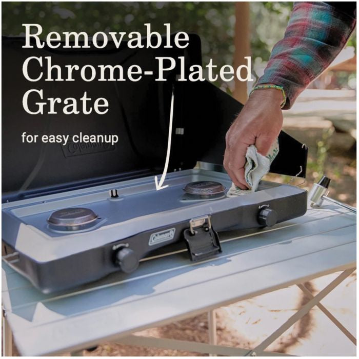 Person cleaning a camping stove with text about a removable chrome-plated grate.