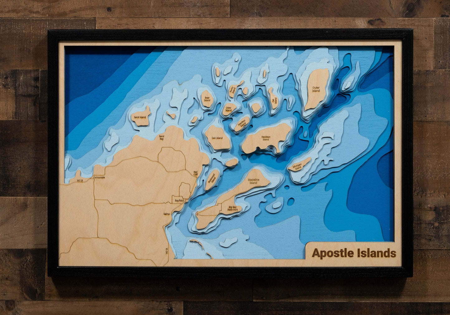 Topographic map of the Apostle Islands in a wooden frame on a wooden wall.