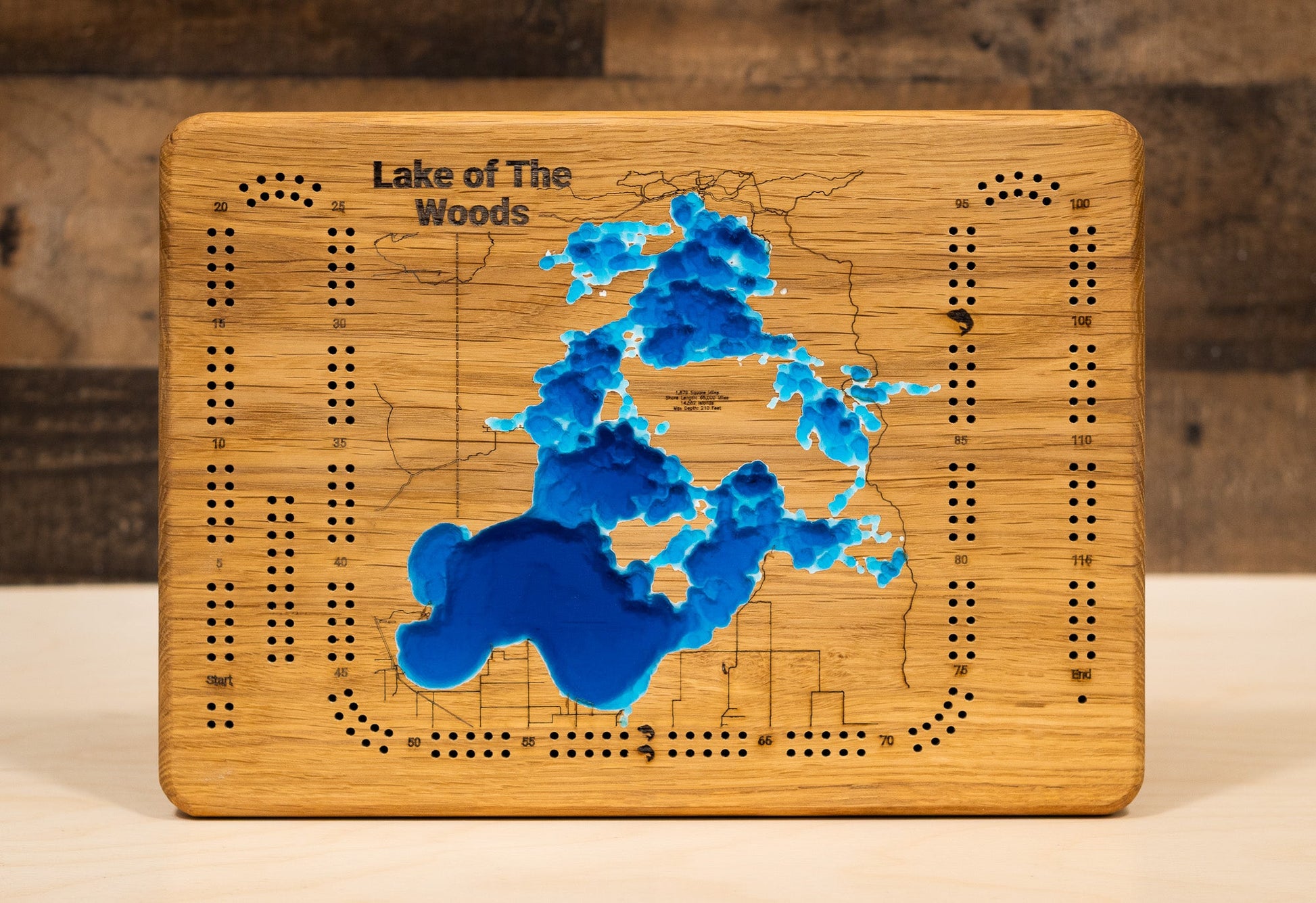 Wooden cribbage board with a map of Lake of the Woods on a wooden surface.